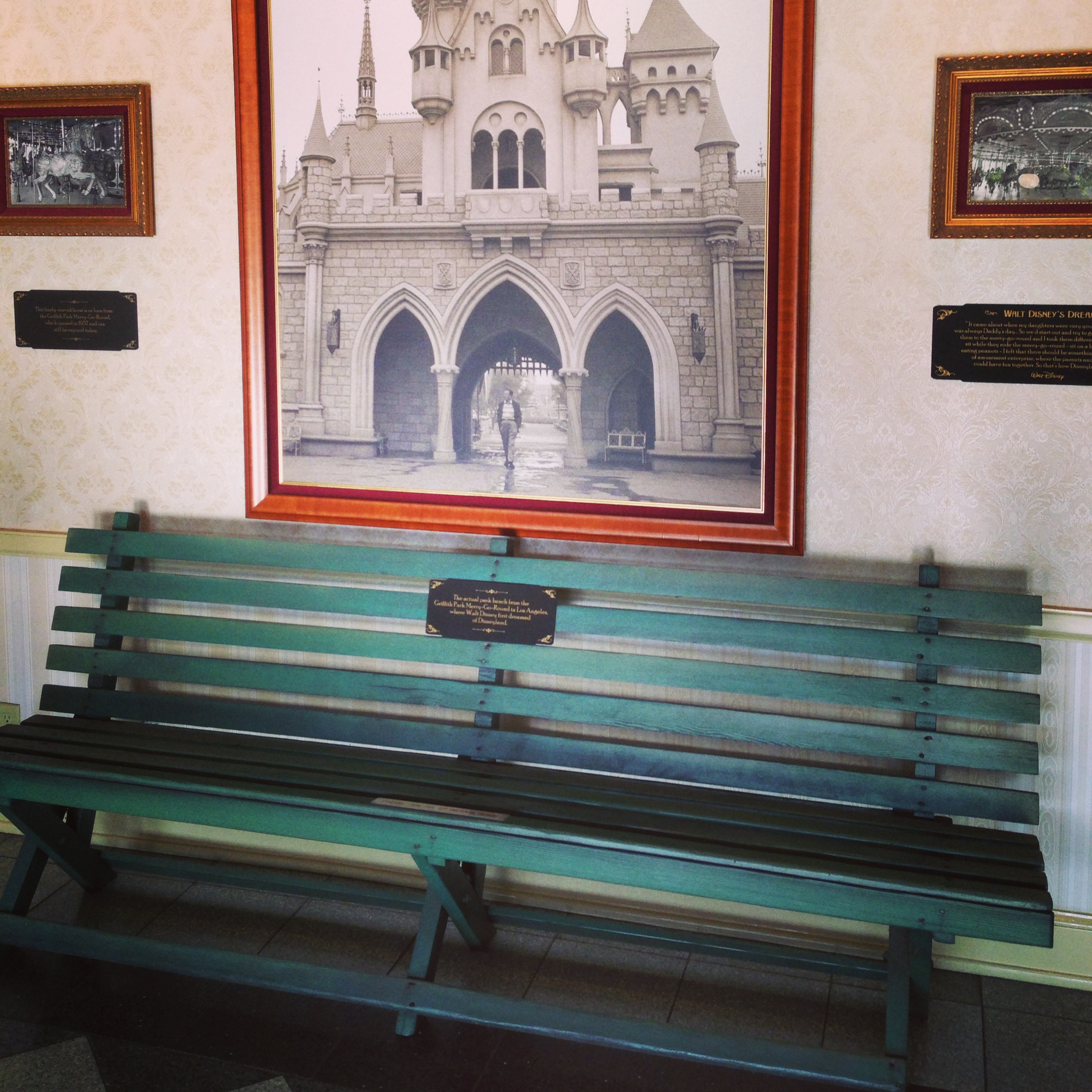 A teal bench sits in front of a picture of the Disney castle.