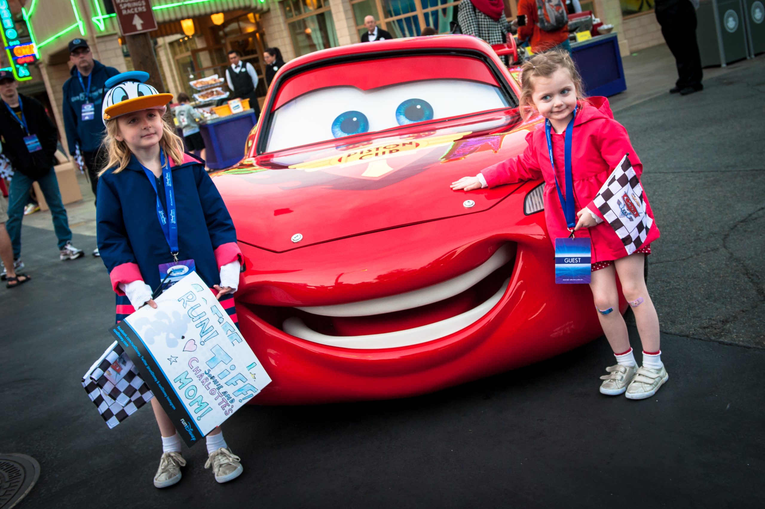 Two young girls stand next to a replica of Lightning McQueen, the race car.