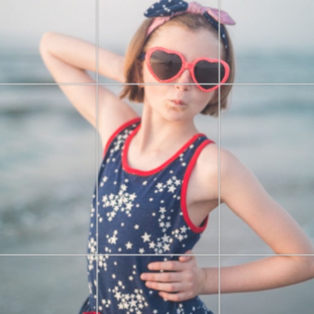 A rule of thirds grid has been overlayed on a photo of a girl at the beach.