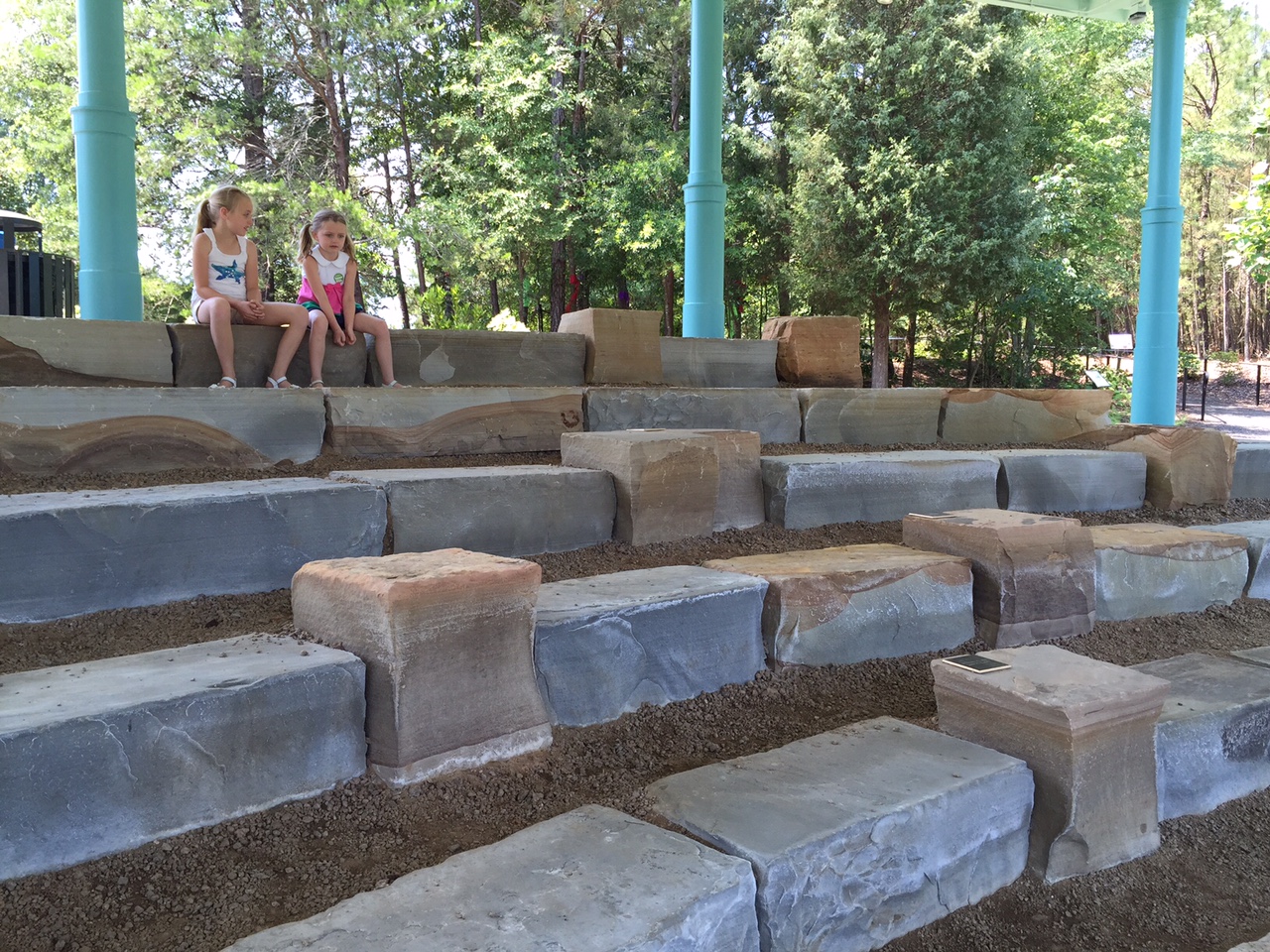 Two young girls sit on the big rock steps at the children's garden.
