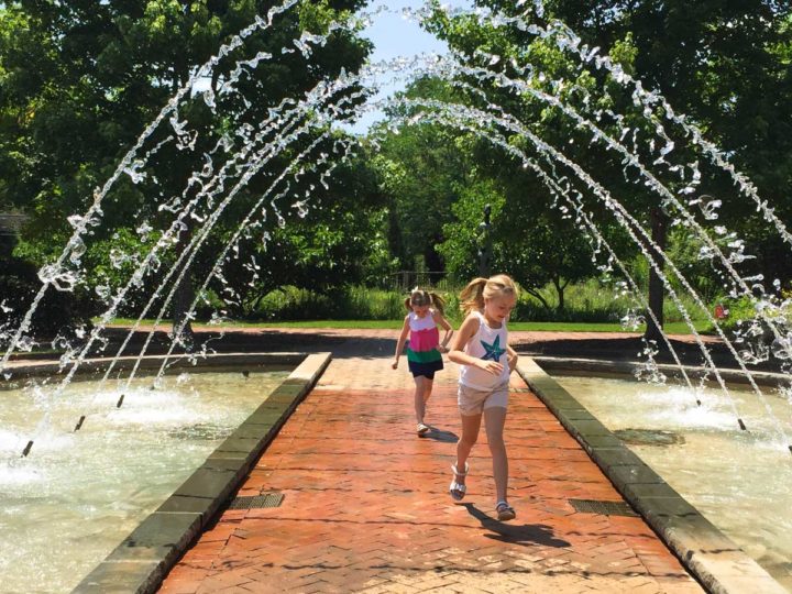 Two young girls run under the arched fountain at the Daniel Stowe Botanic Garden.