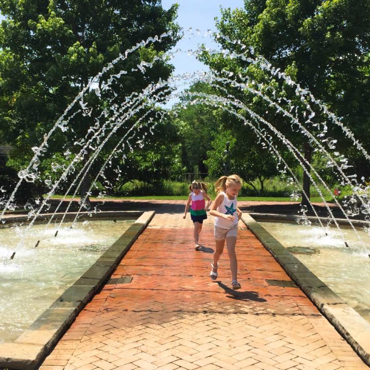 Two young girls run under the arched fountain at the Daniel Stowe Botanic Garden.