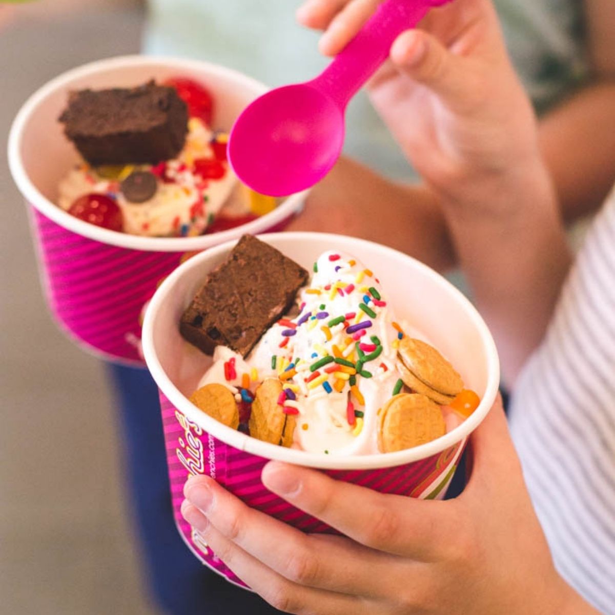 Two ice cream sundaes about to be eaten.