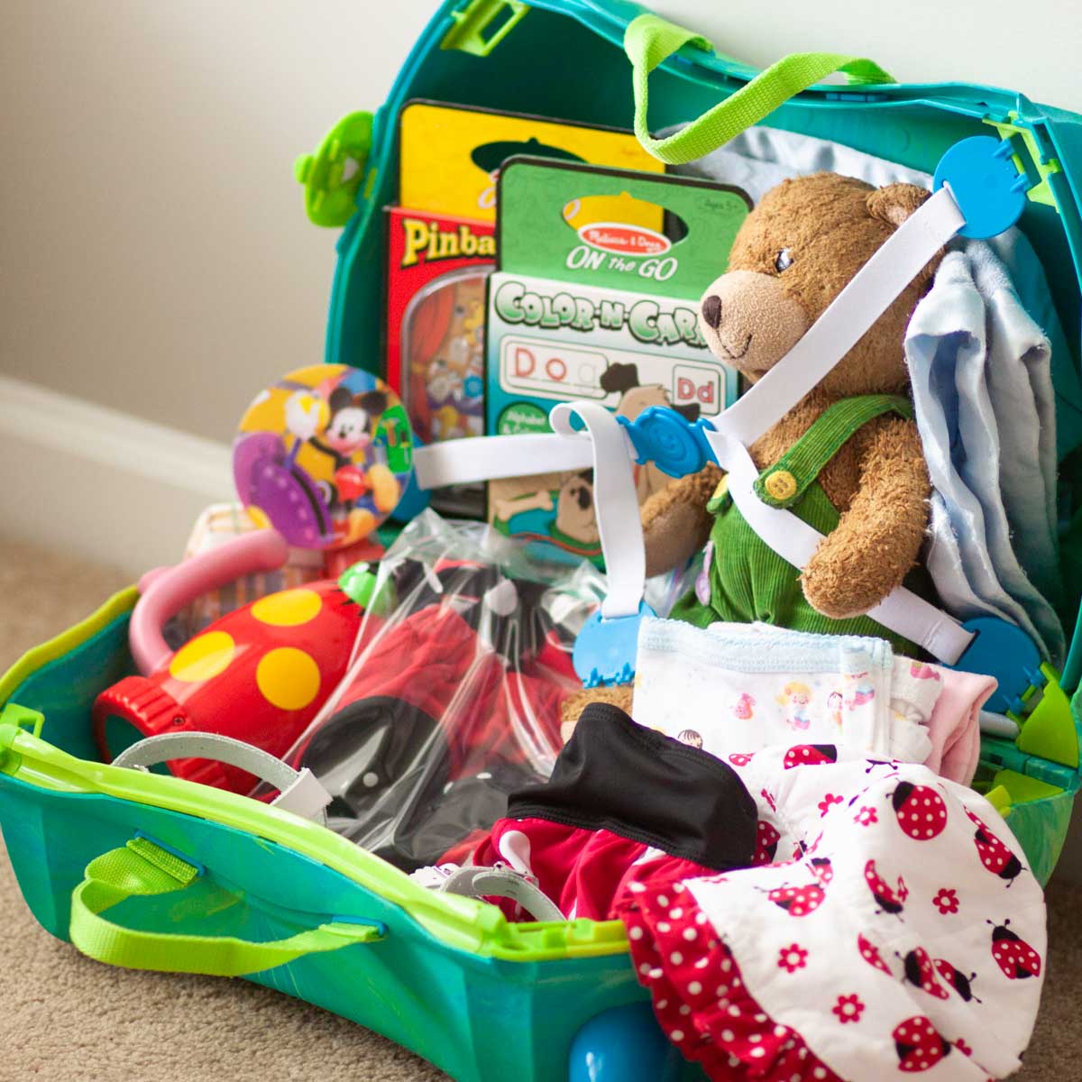 A kids' suitcase is filled with clothing and a few toys.