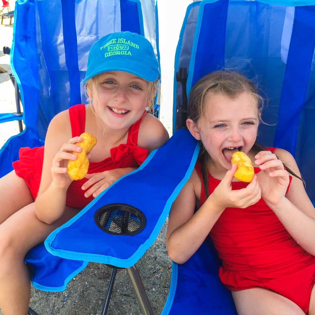 Two young girls enjoying Twinkies in beach chairs.