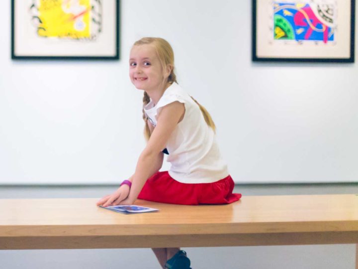 A young girl sits on a bench at Charlotte's Mint Museum.