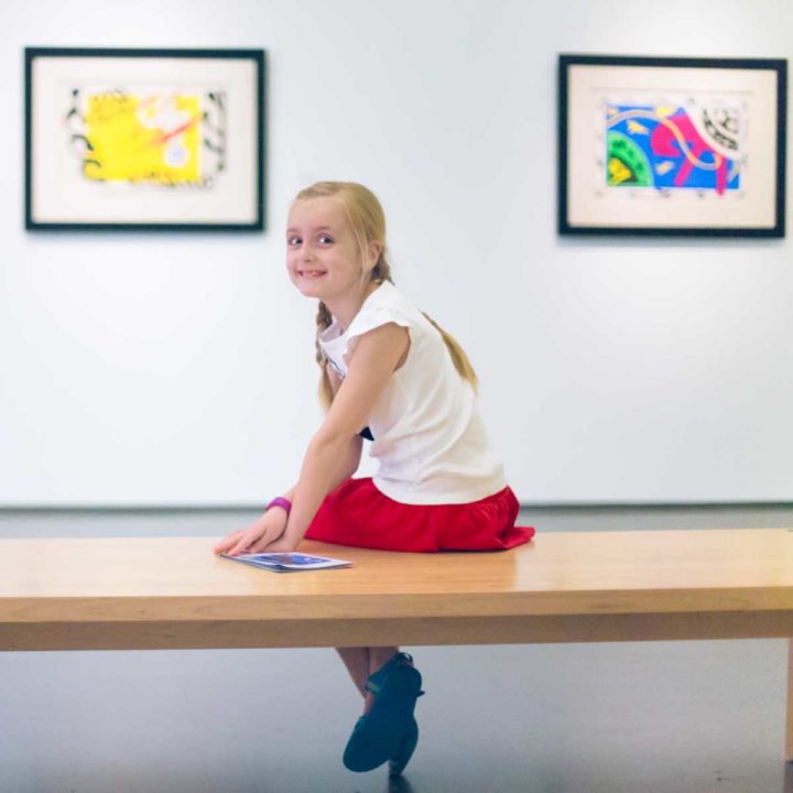 A young girl sits on a bench at Charlotte's Mint Museum.