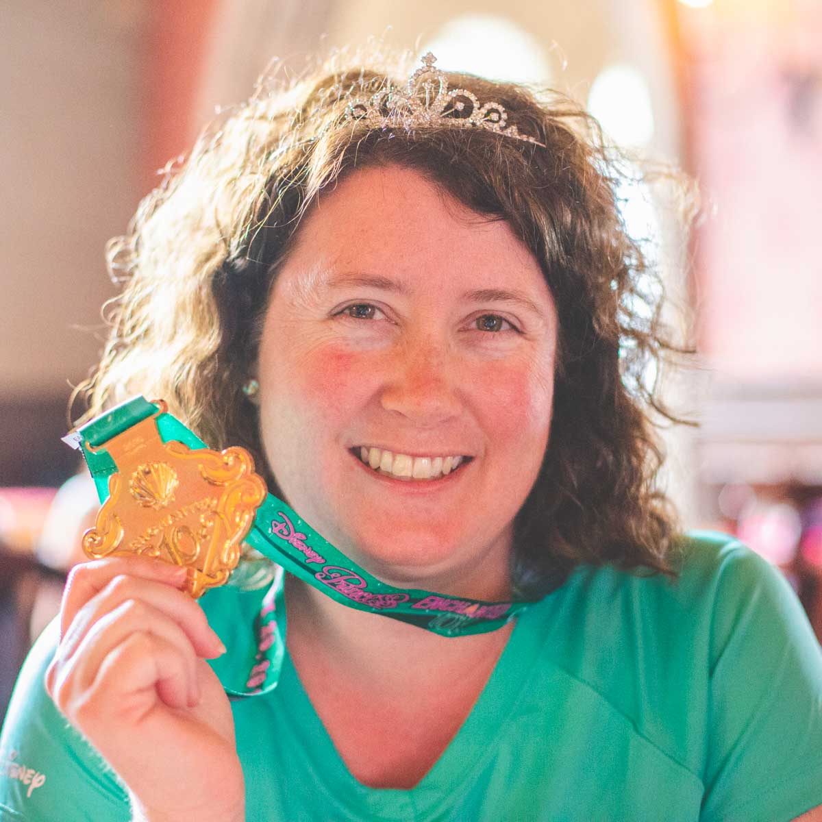 A runner poses with her runDisney medal after running the Enchanted 10K.