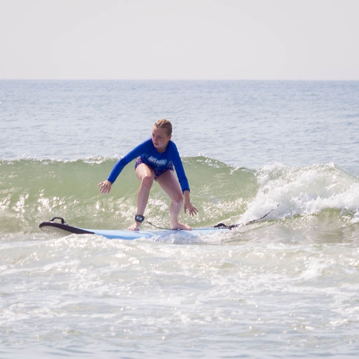 A young girl surfing at camp.