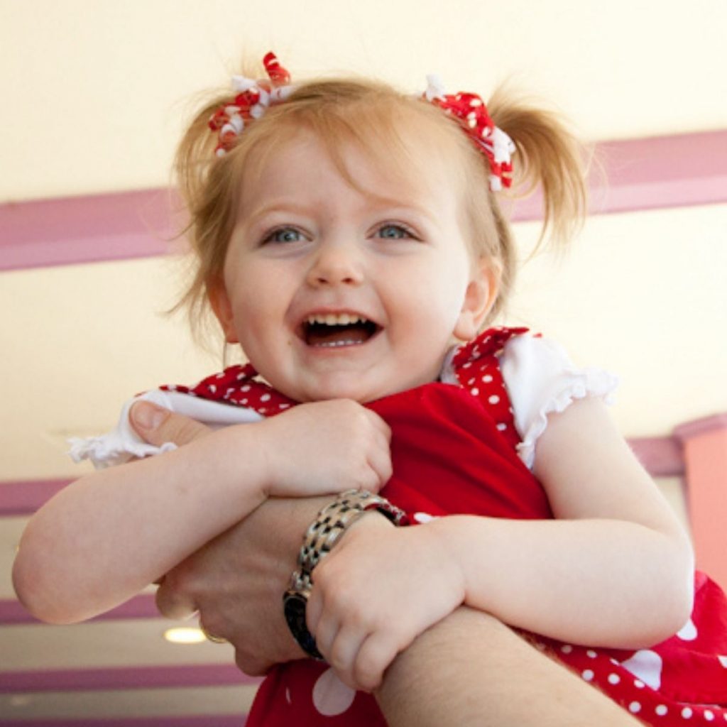 A toddler is being held up by her dad to see the crowd at Disney.