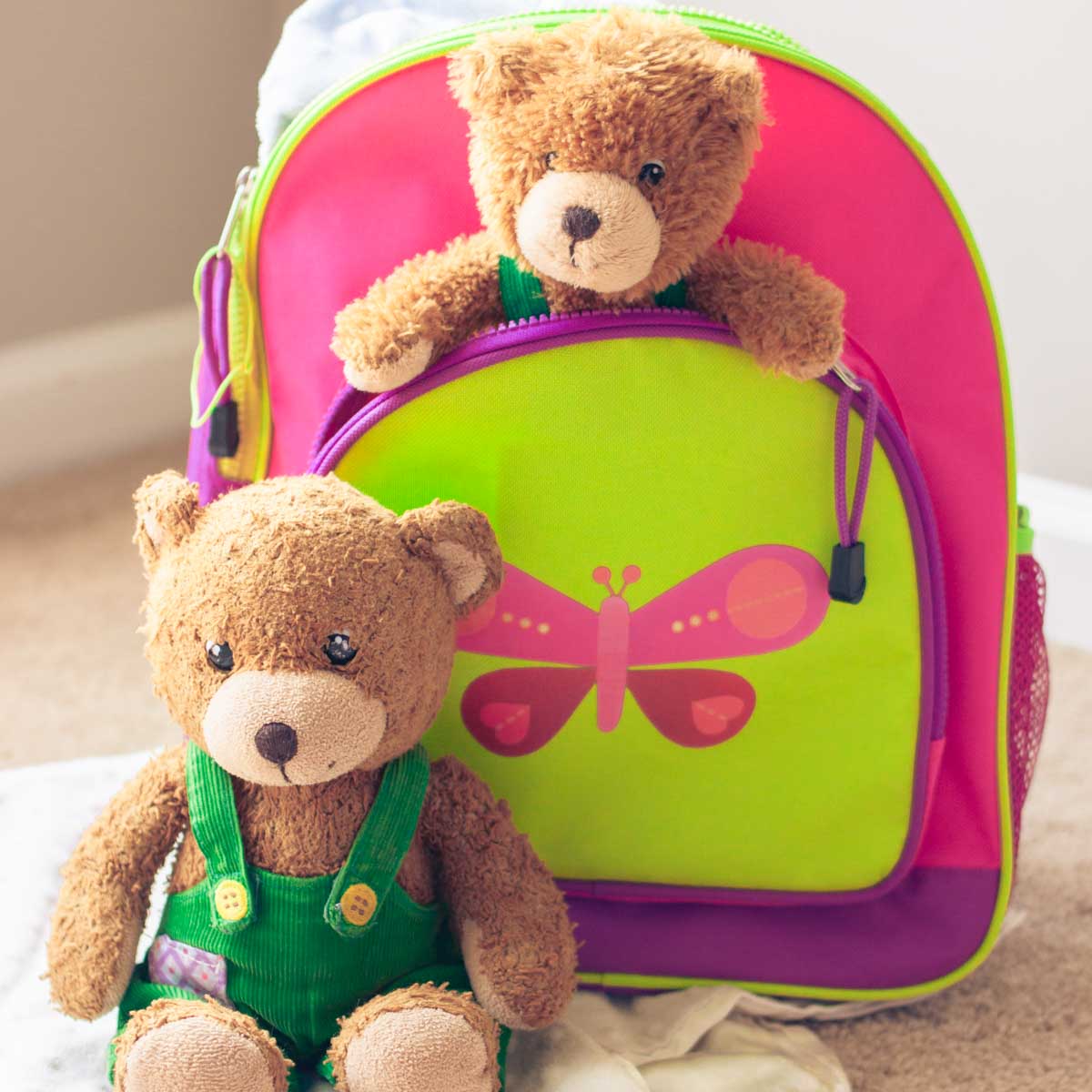 A spare stuffed bear for travel is in a backpack while the original bear stays home.