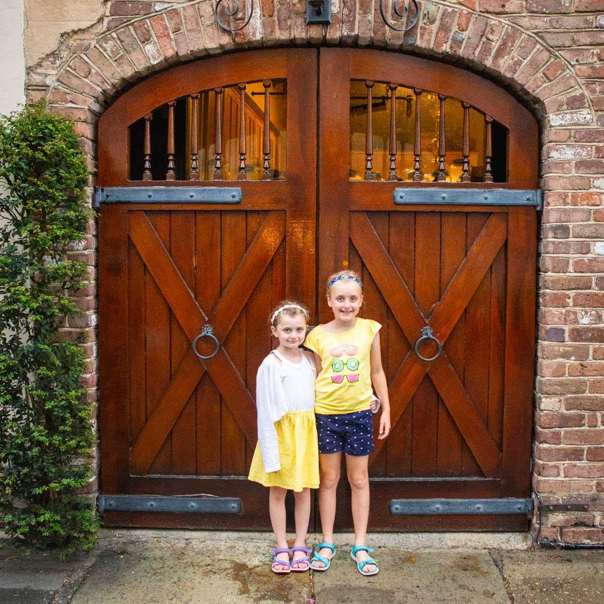 Two young girls stand in front of a decorative gate on vacation.