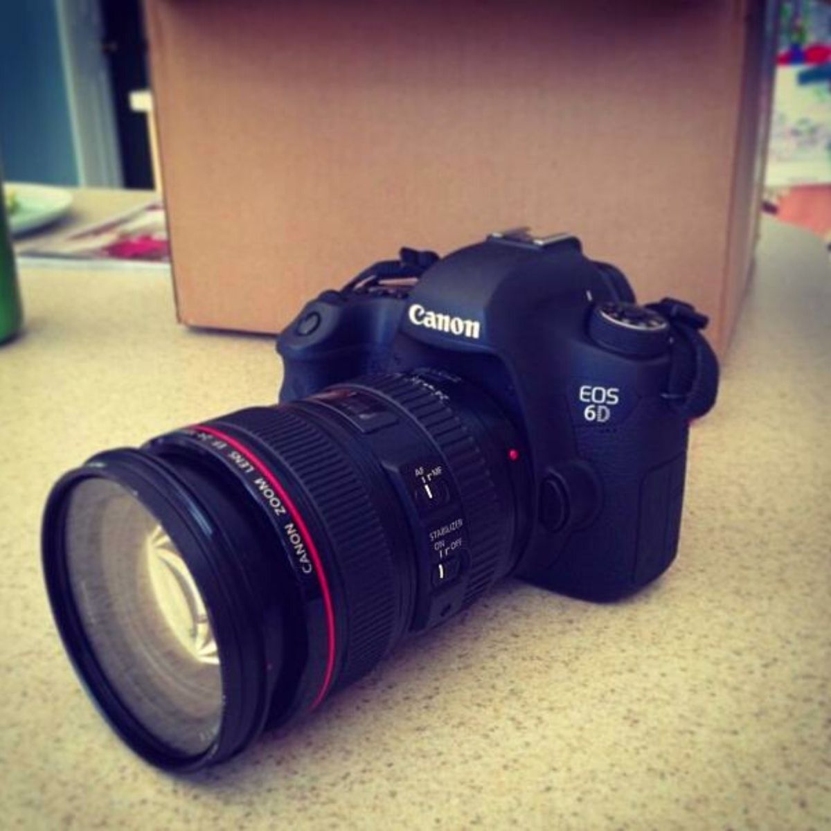 A rental lens is on the body of my camera and sitting on the counter.