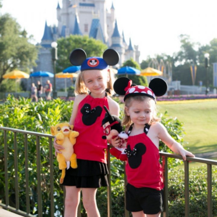 Two girls wear matching Disney outfits they got as a gift before the trip.