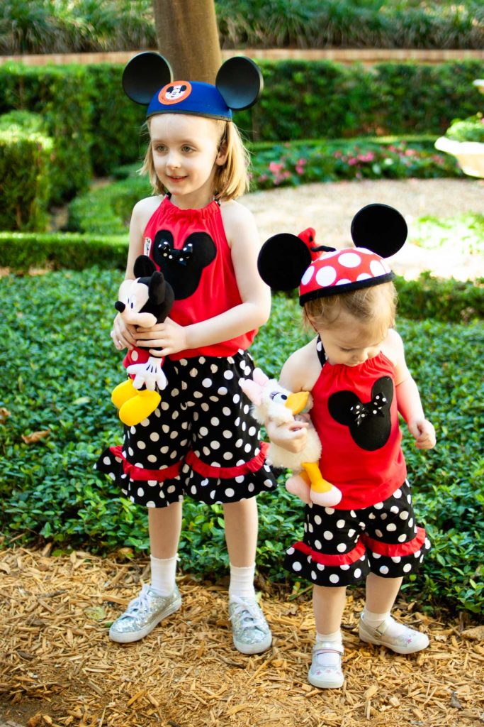 Two young girls pose in matching outfits at the Disney Parks.