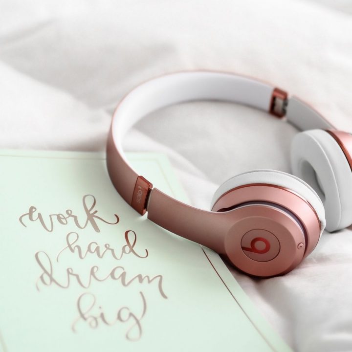 A pair of pink headphones sits next to a sign that says: "Work hard, Dream big"