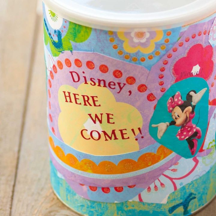 A DIY Disney savings jar is covered in colorful papers.