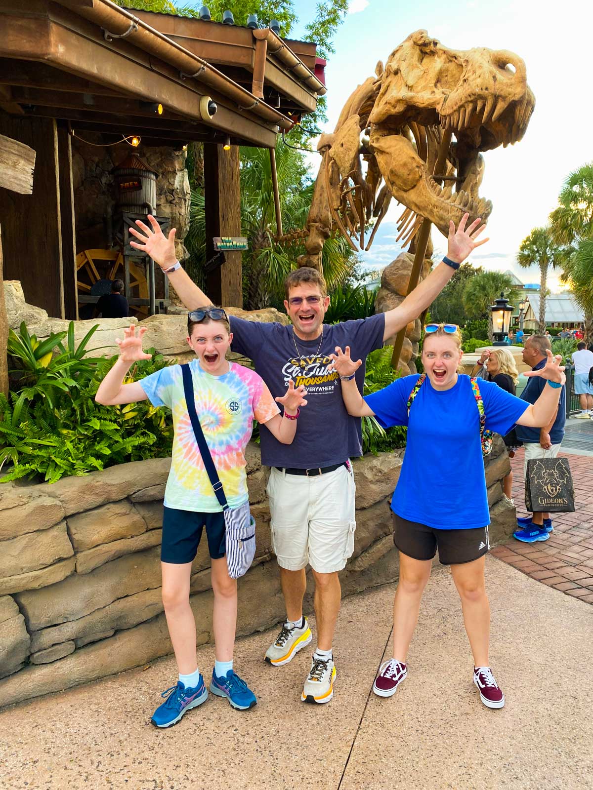 A family stands in front of a dinosaur statue and ROARS