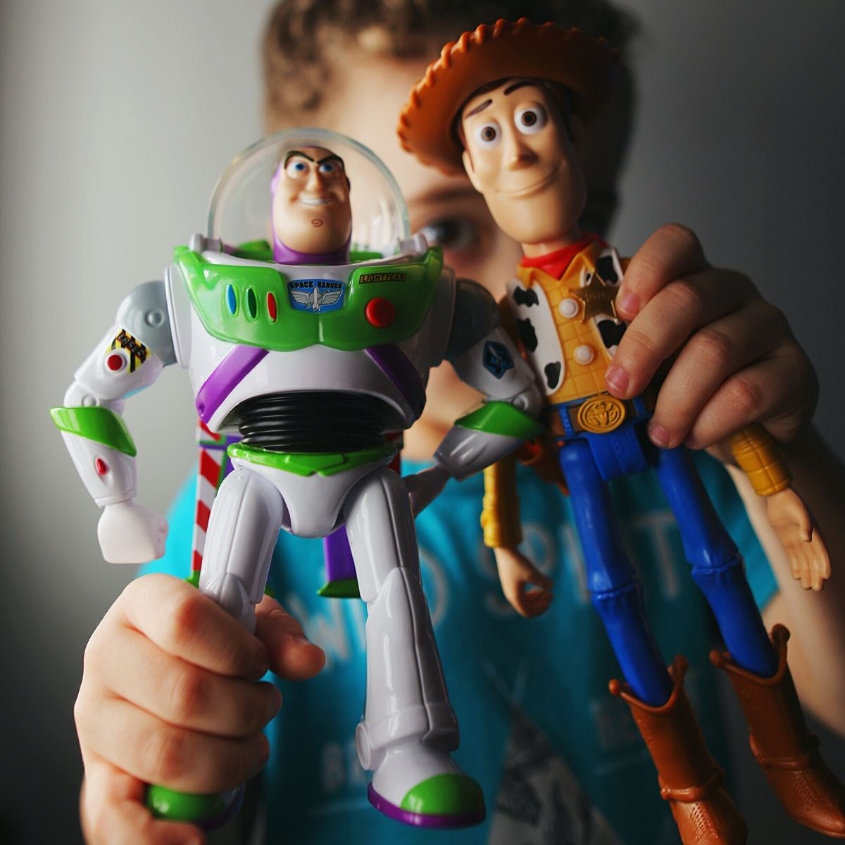 A young boy holds two Toy Story Toys.