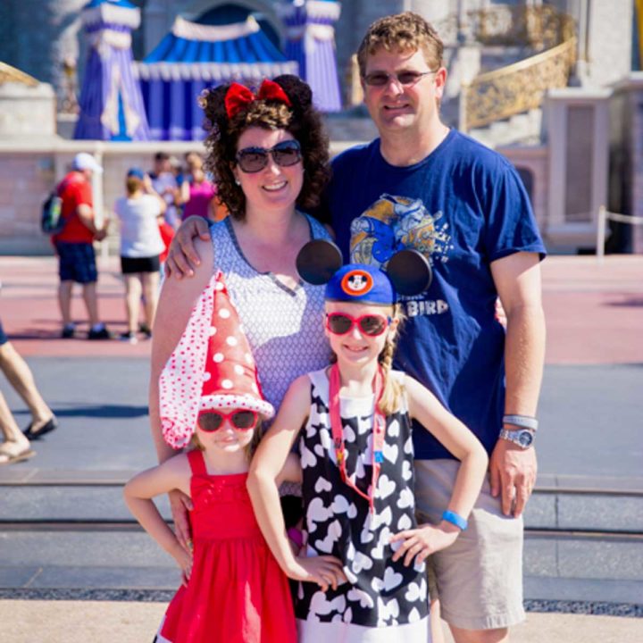 A family of four stands in front of the Disney castle in Florida.