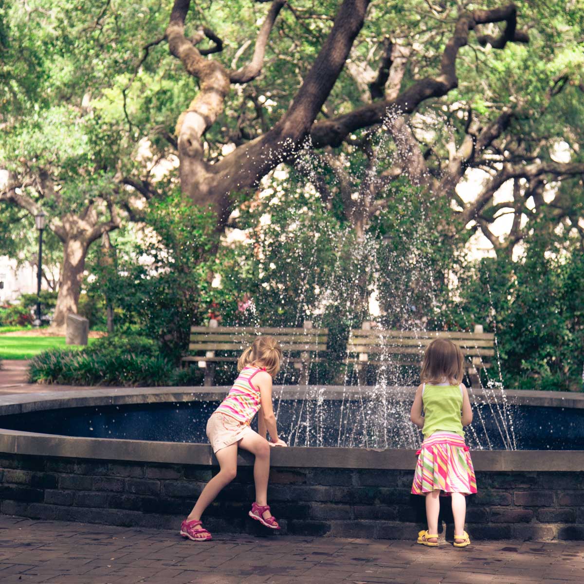 Two young girls look into a fountain in the main square of Savannah, Georgia.