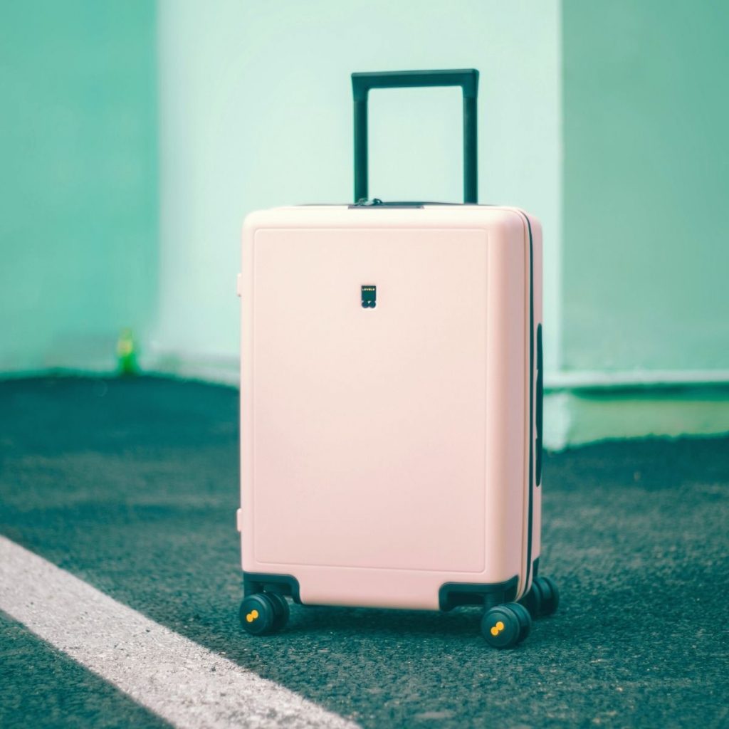 A pink suitcase with the handle extended.