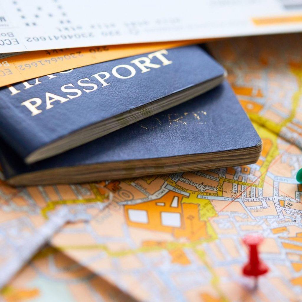 Passports sit on a paper map with pushpins.