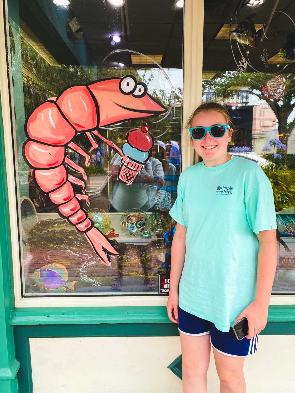 A young girl poses next to a large shrimp decoration outside a store in Amelia Island.