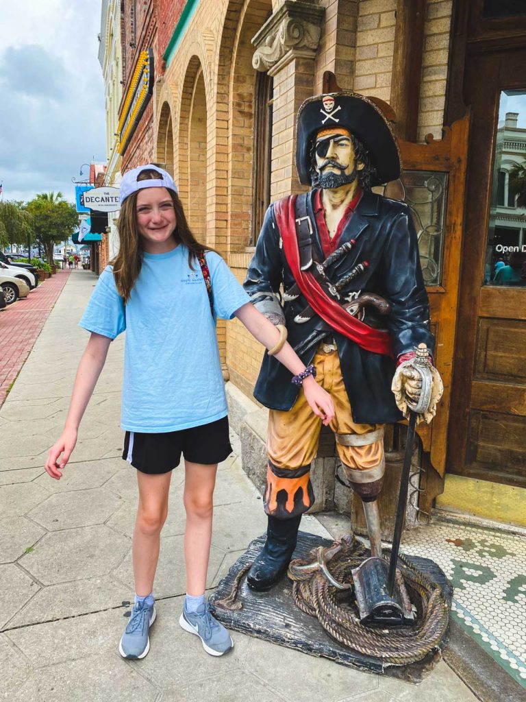 A girl poses next to a pirate statue.