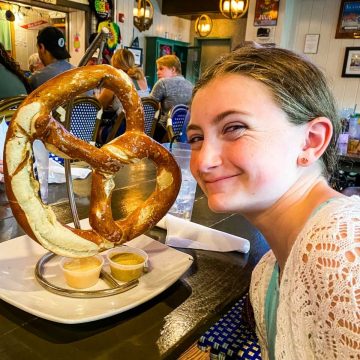 A young girl is about to eat a pretzel as big as her head.