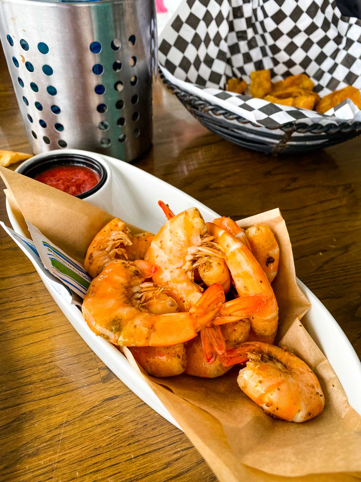 A platter of peel and eat shrimp with cocktail sauce.