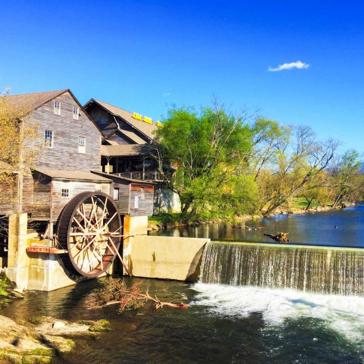 The old mill sits next to a waterfall.
