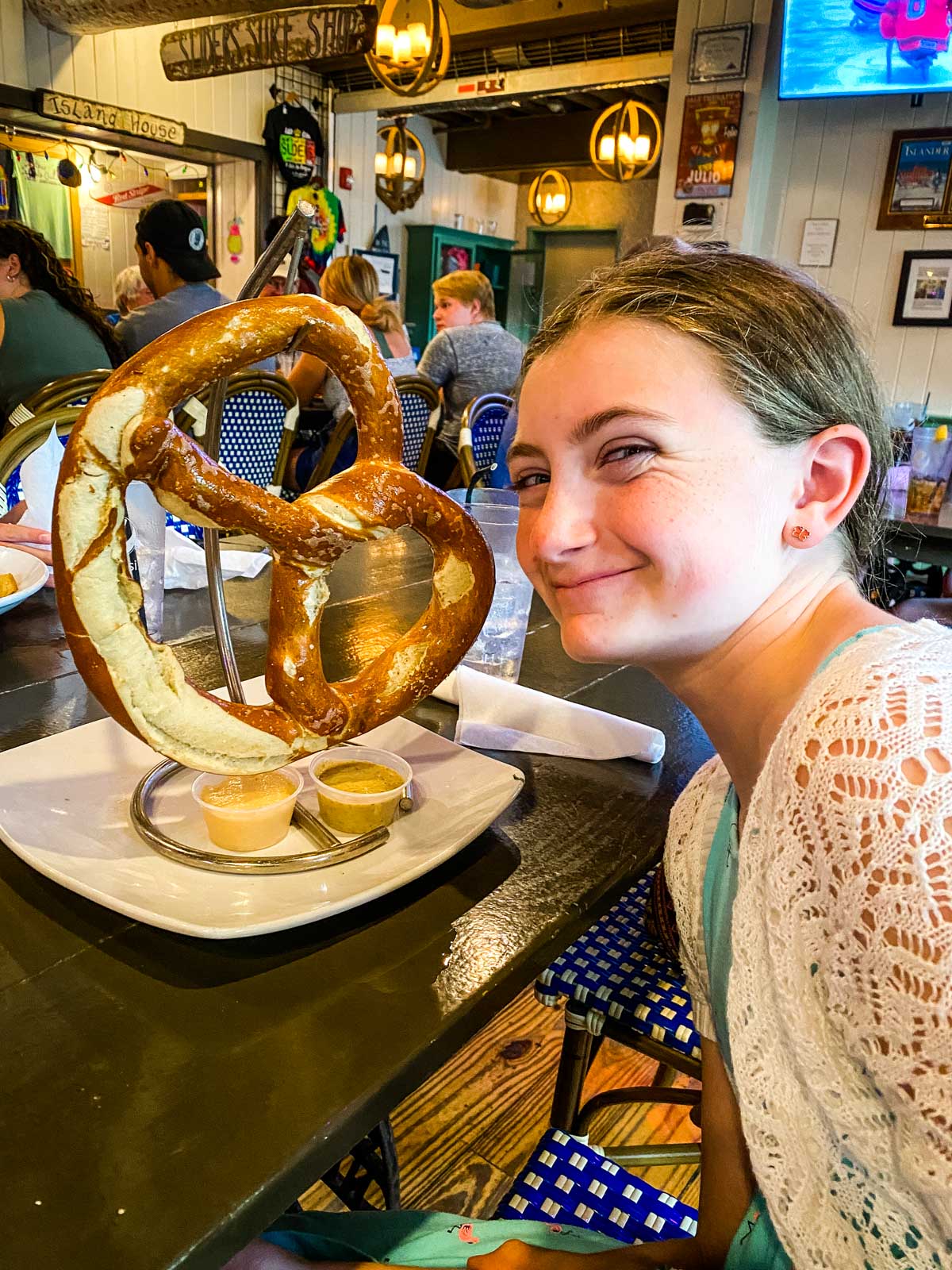 A young girl is about to eat a giant pretzel as big as her head.