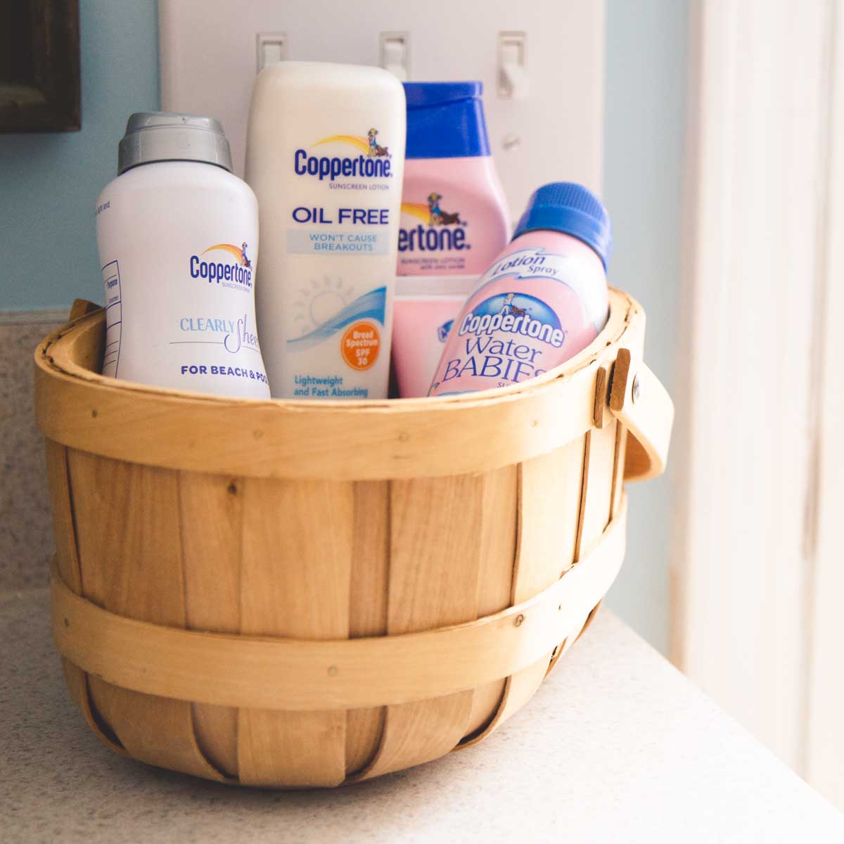 A basket filled with bottles of sunblock sits on a counter.