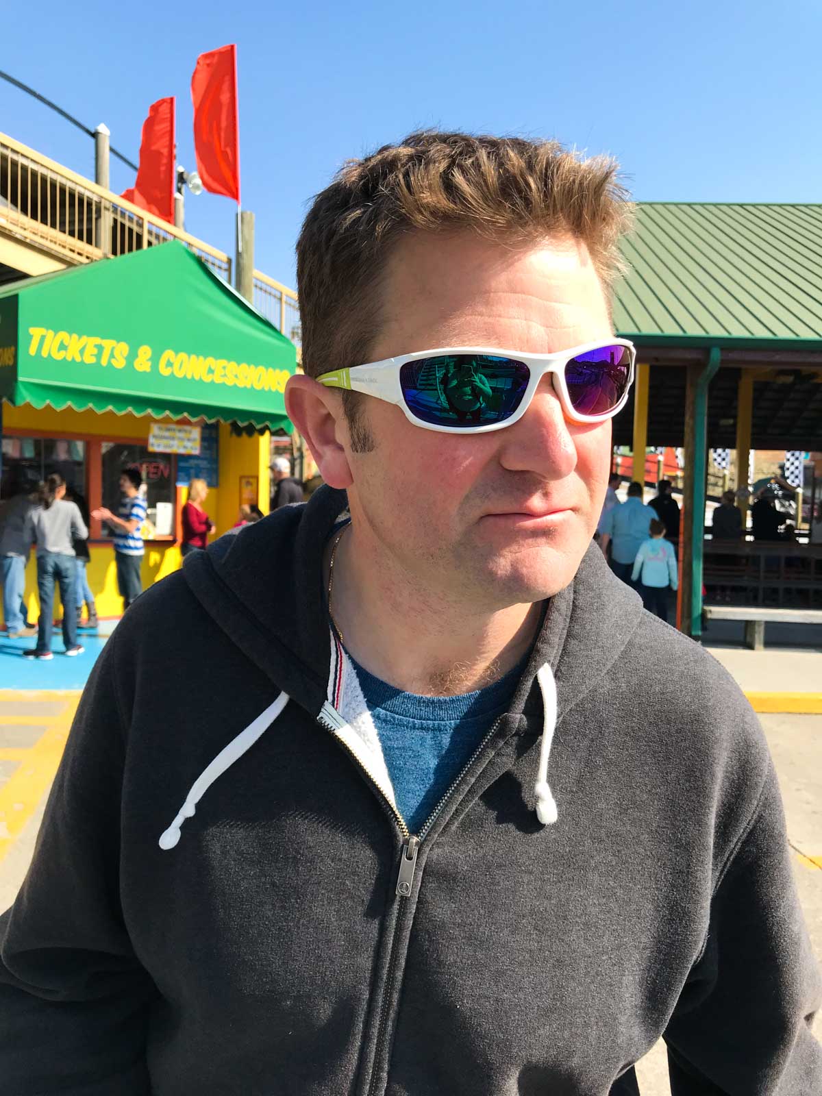 My husband Tim is wearing sunglasses and doing a silly pose standing in line at The Track.