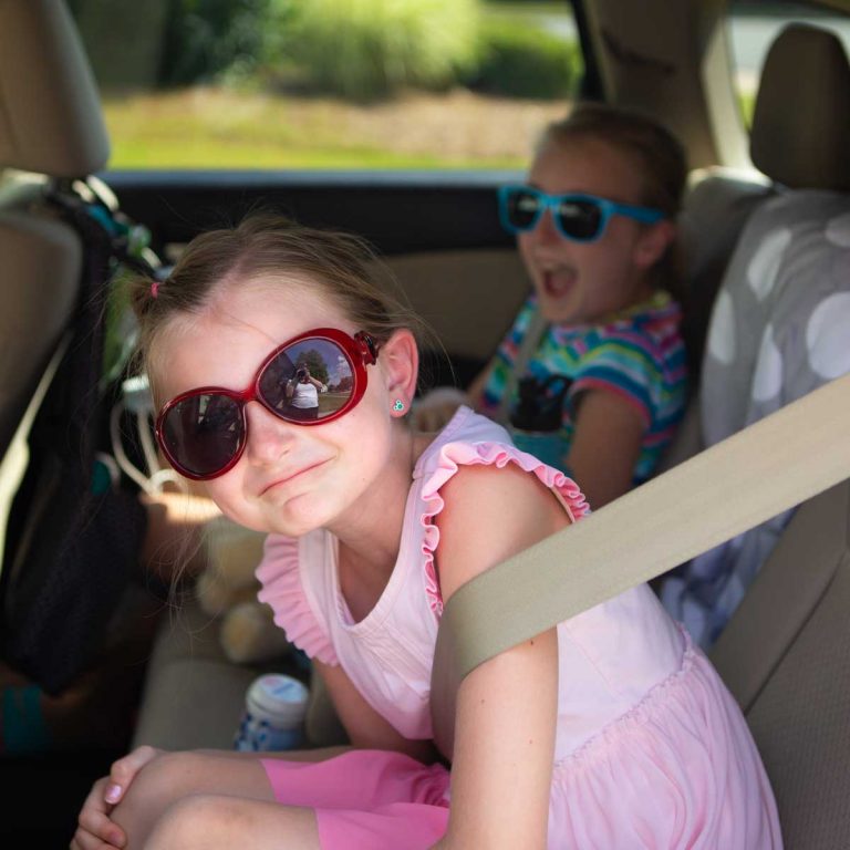 Two girls in the back seat of a car for a road trip.