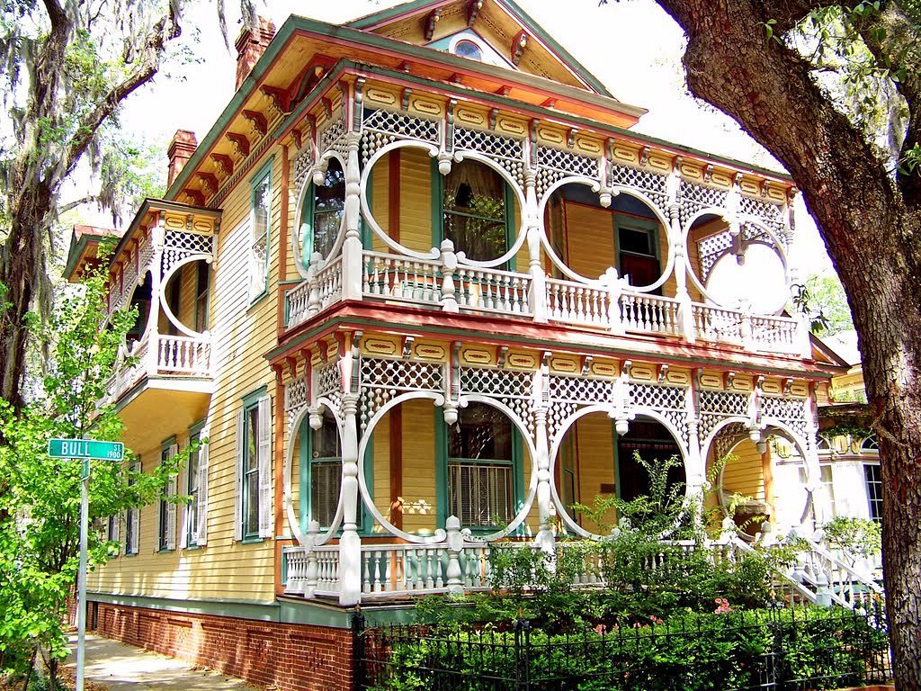 A gingerbread style yellow house with elaborate white painted railings.