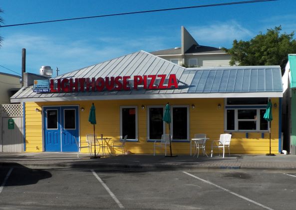 The front of the pizza restaurant is yellow with a blue door.
