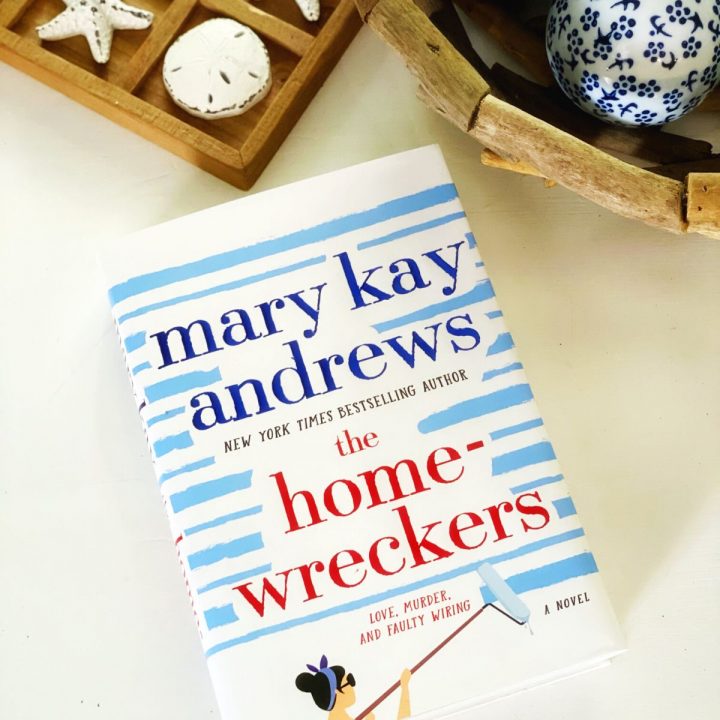 A copy of the book The Homewreckers sits on a white table next to beachy accessories.
