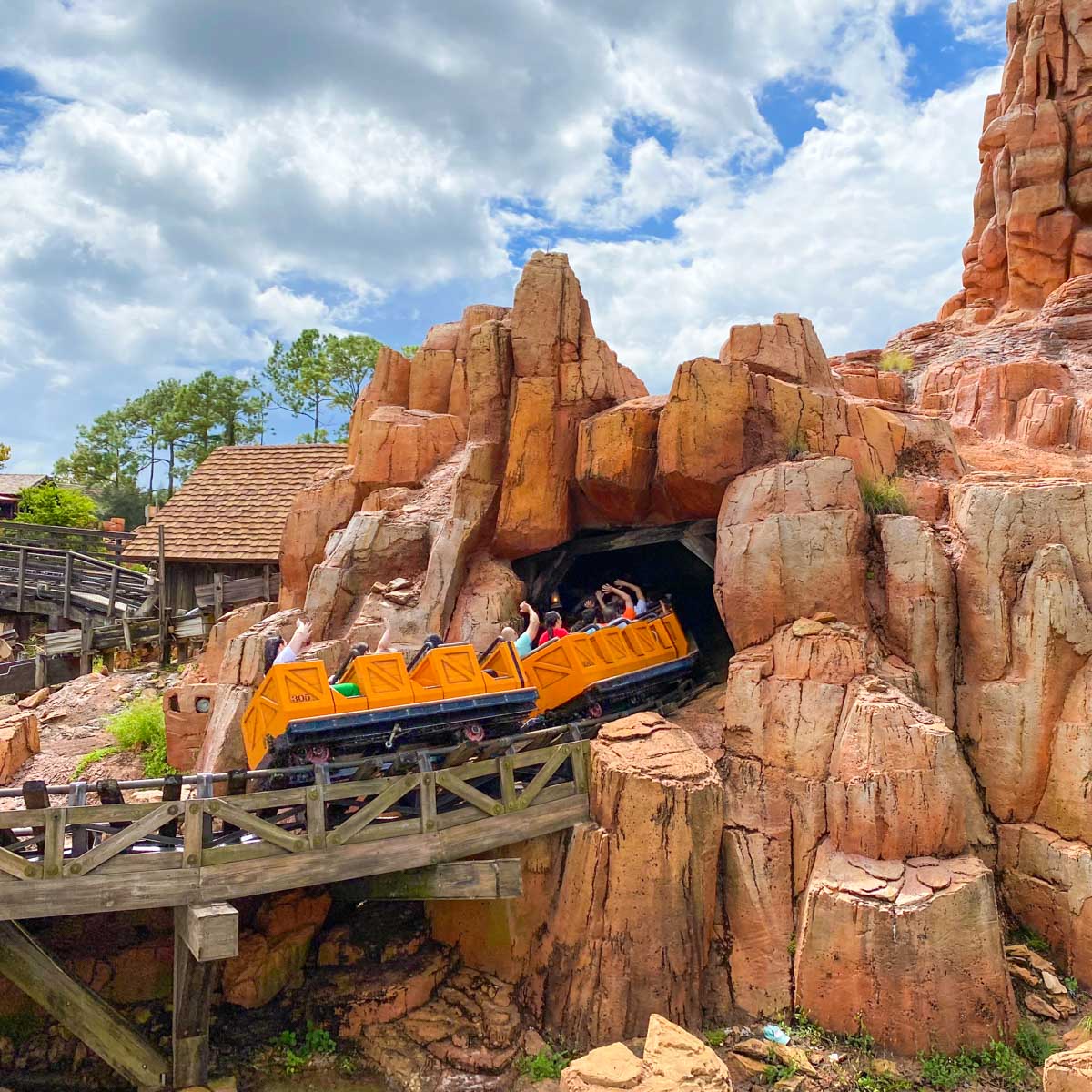 A roller coaster disappears into a cave in a mountainside on Big Thunder Railroad in Magic Kingdom.