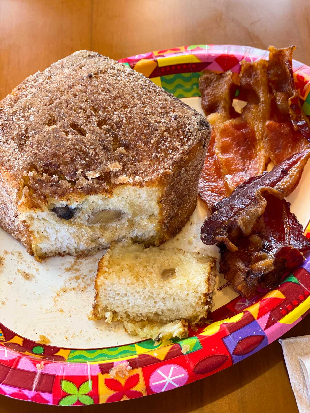 A breakfast platter with fried French toast is cut open to see the bananas inside. Bacon on the side.