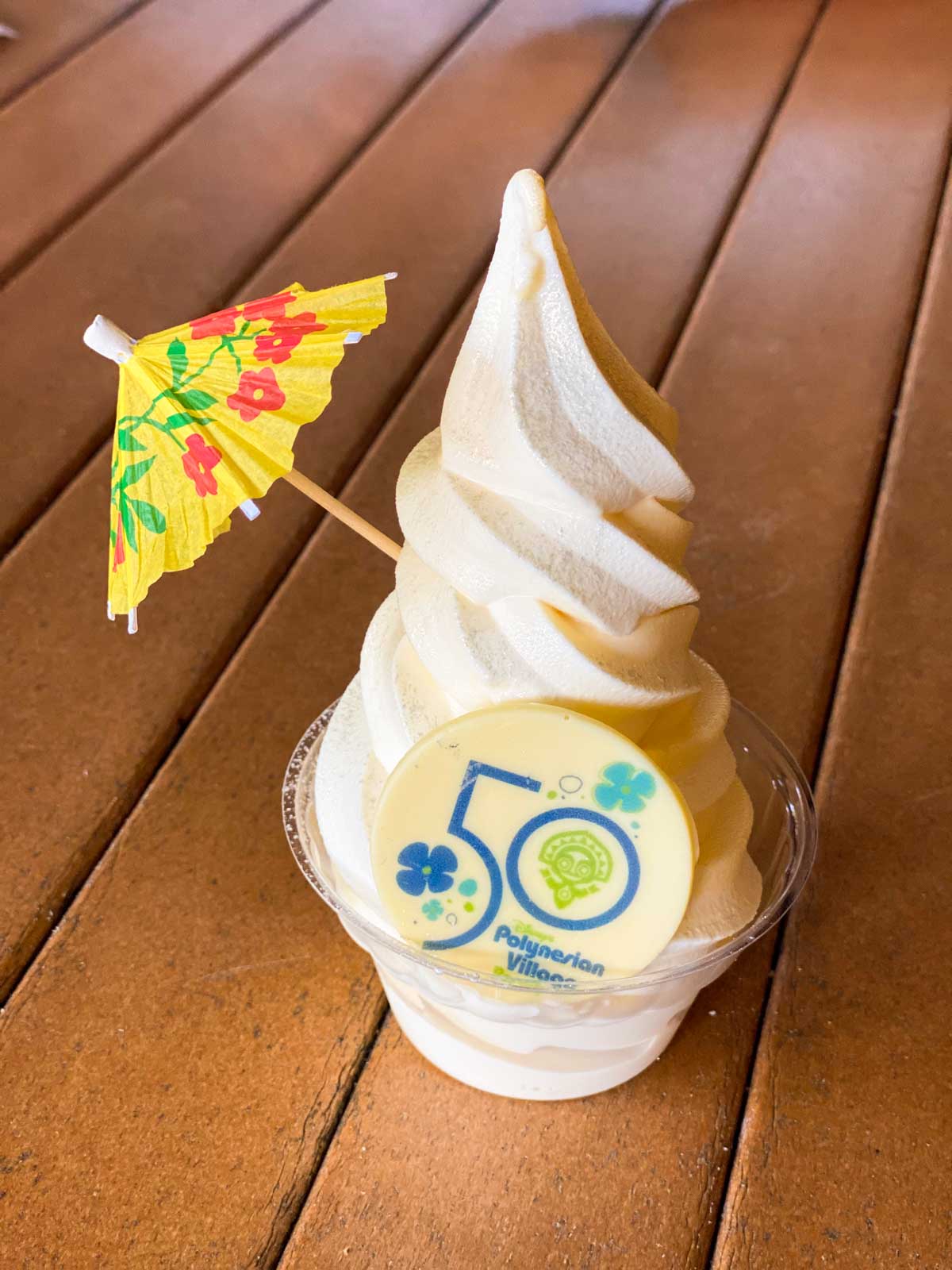 A frozen Dole whip with a yellow umbrella and a 50th anniversary chocolate coin.