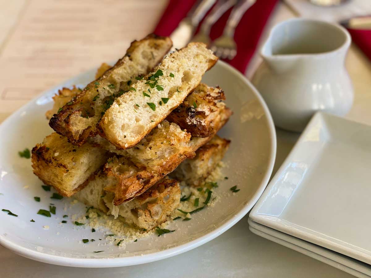 The garlic bread is cut into long fingers and served with a cheese sauce for dipping.