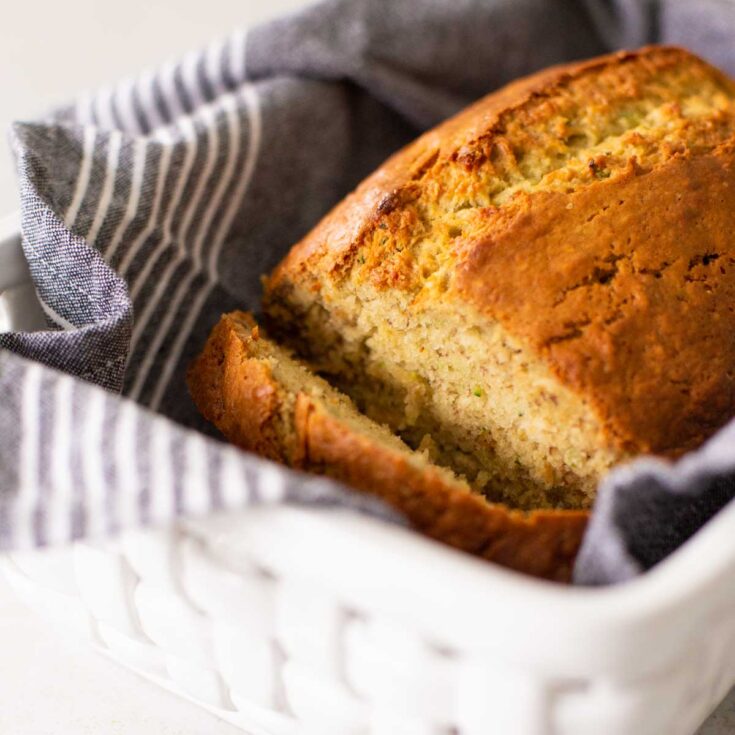 A loaf of banana bread in a basket with a napkin.