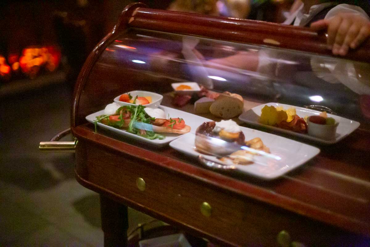 A wooden cart with glass dome brings the food.
