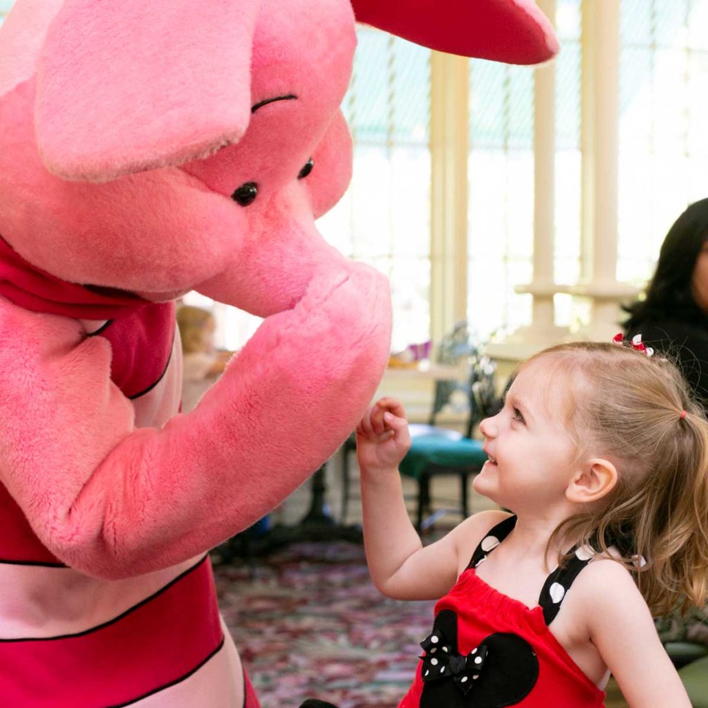 Piglet plays with a young girl wearing a Mickey top.