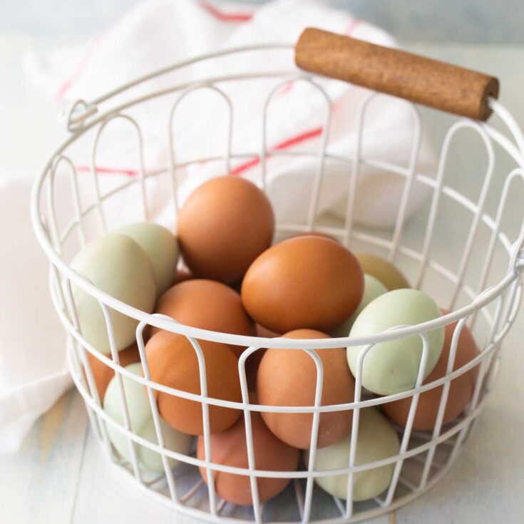 A white wire basket holds brown and blue eggs.
