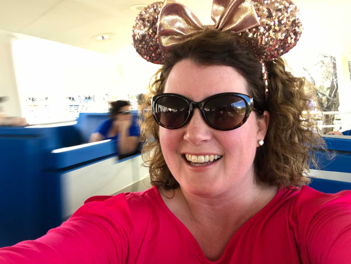 A woman with Minnie Ears rides the people mover.