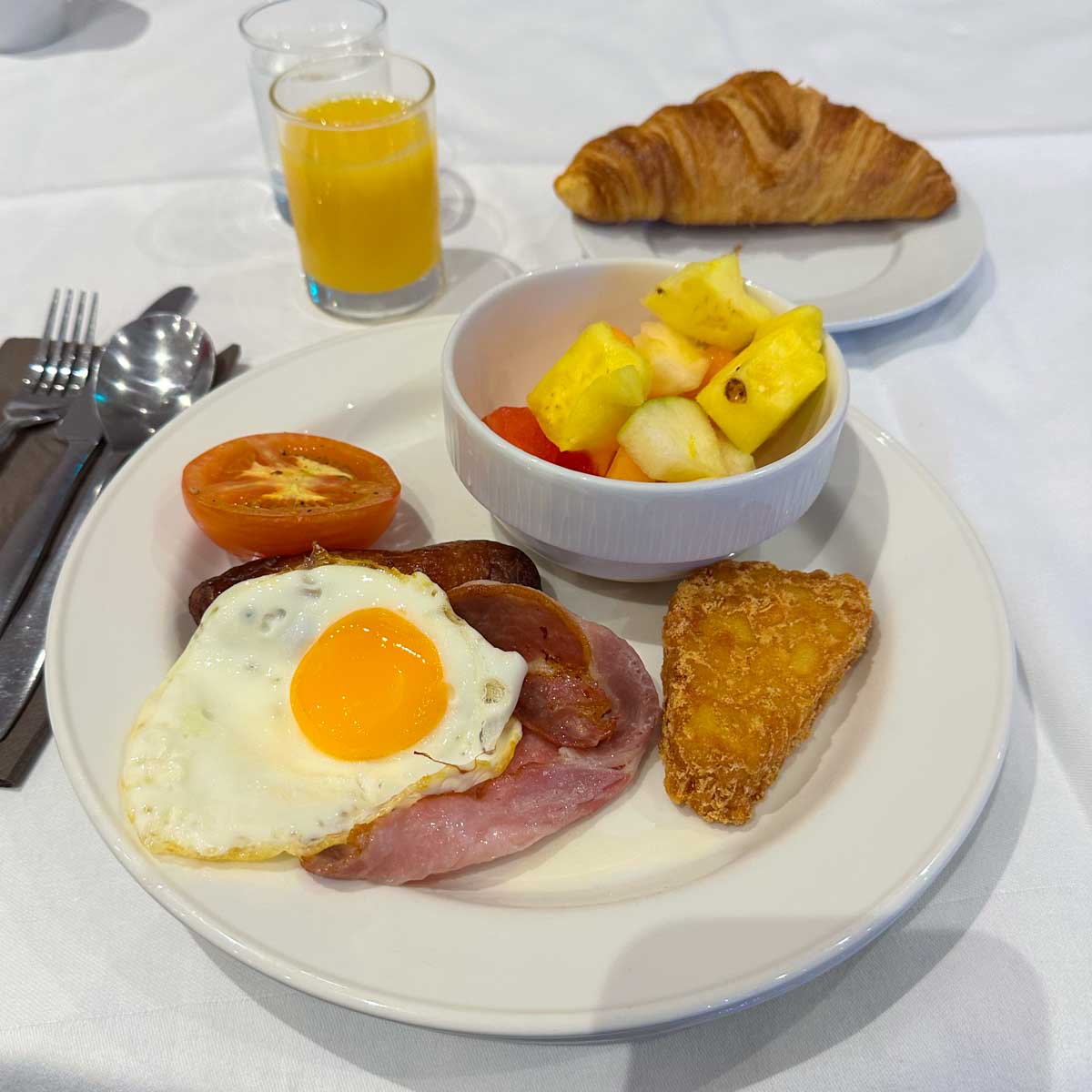 A breakfast plate at an Irish hotel serves the traditional breakfast of fried egg with ham, hashbrown, and tomato.
