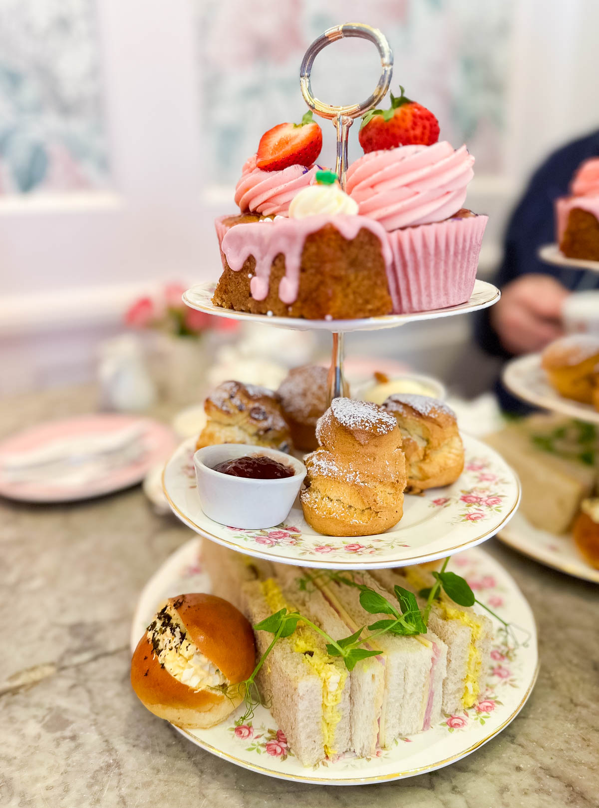 A 3-tier tray of tea time sandwiches and pastries at a tea shop in London.